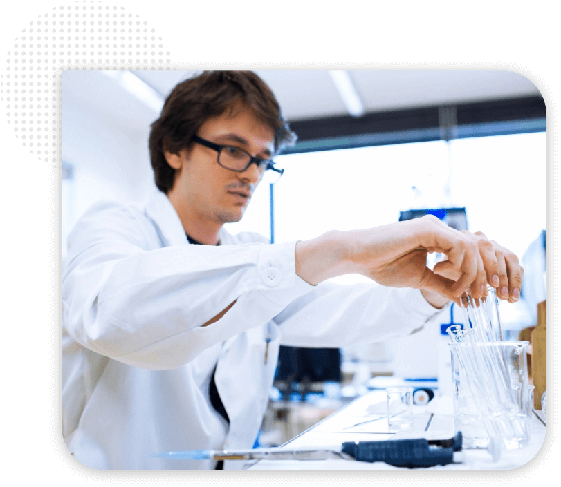 A man in glasses and lab coat working with some liquid.